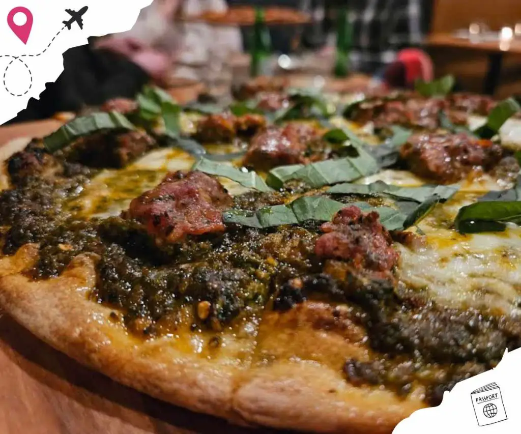 Freshly baked pizza with basil leaves and meat toppings at a restaurant for travel and food tourism.