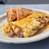 Savory breakfast scramble with bacon, shredded cheese, and toast on a white plate, perfect for morning meals and travel dining experiences.