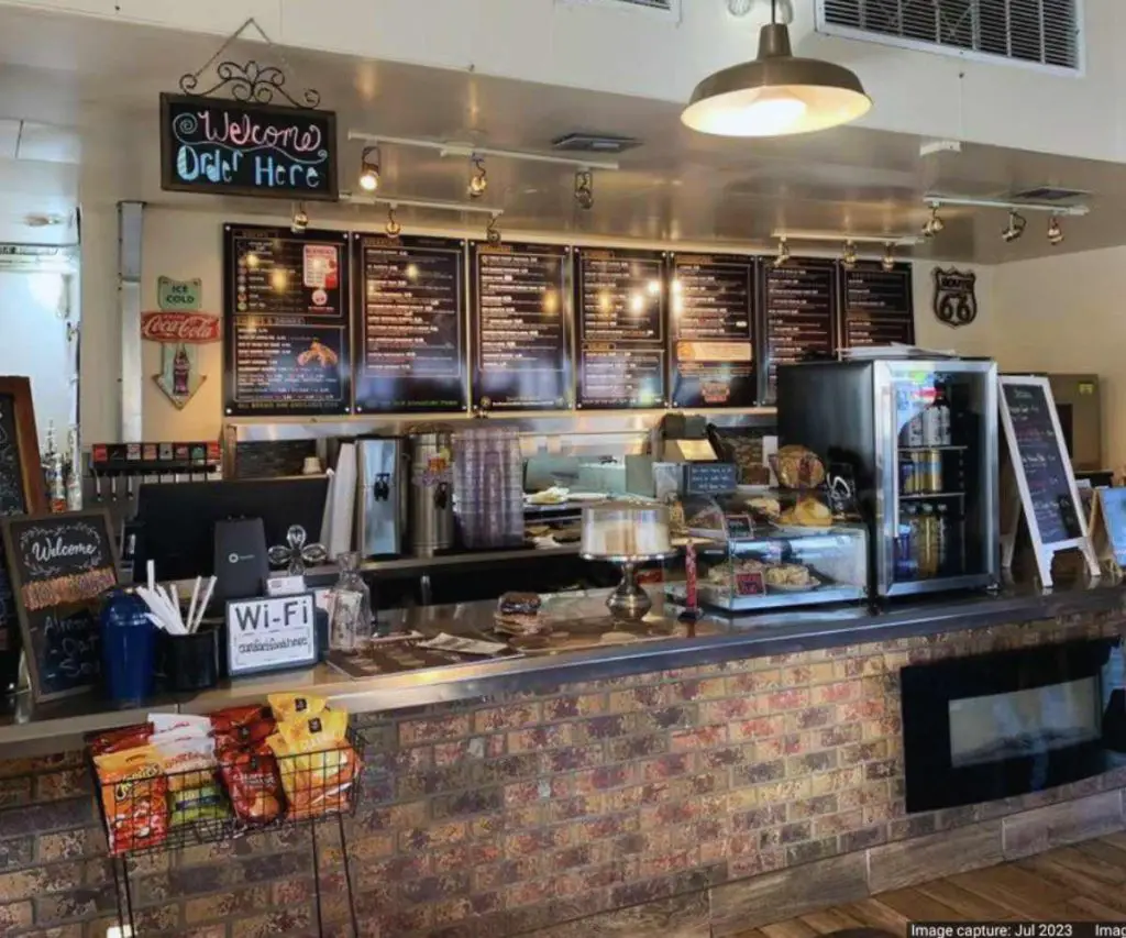 Order coffee and food at a cozy café with a vintage-inspired brick counter, digital menu boards, and inviting decor, perfect for travel and exploring local destinations.