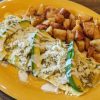 Crispy breakfast burrito with zucchini slices, cheese, and white sauce on a yellow plate, served with home-fried potatoes, popular breakfast meal, hearty brunch dish, comfort food, morning meal, easy breakfast recipe.