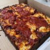 Cheesy pepperoni pizza slice in a cardboard box, close-up view, ideal for pizza lovers, featuring melted cheese, crispy crust, and savory tomato sauce. Perfect comfort food from Italy.