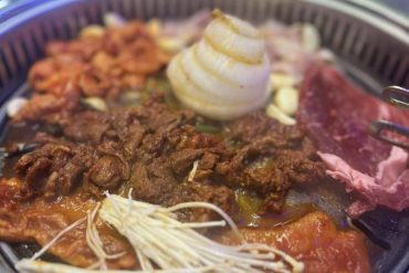 Ground beef, chicken, and beef on a grill with vegetables and mashed potatoes with butter, close-up of grilled meat and side dishes on a barbecue plate, delicious outdoor meal perfect for travel and food enthusiasts.