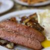 Grilled breakfast plate featuring sausage, eggs, and crispy potatoes for a delicious morning meal. Perfect for travel lovers exploring local cuisines and travel destinations.