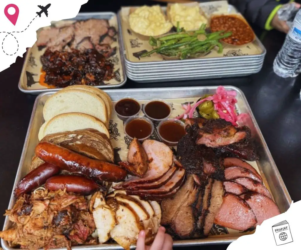 Bbq platter with smoked meats, sausages, bread, and side dishes on a metal tray for authentic American barbecue experience.
