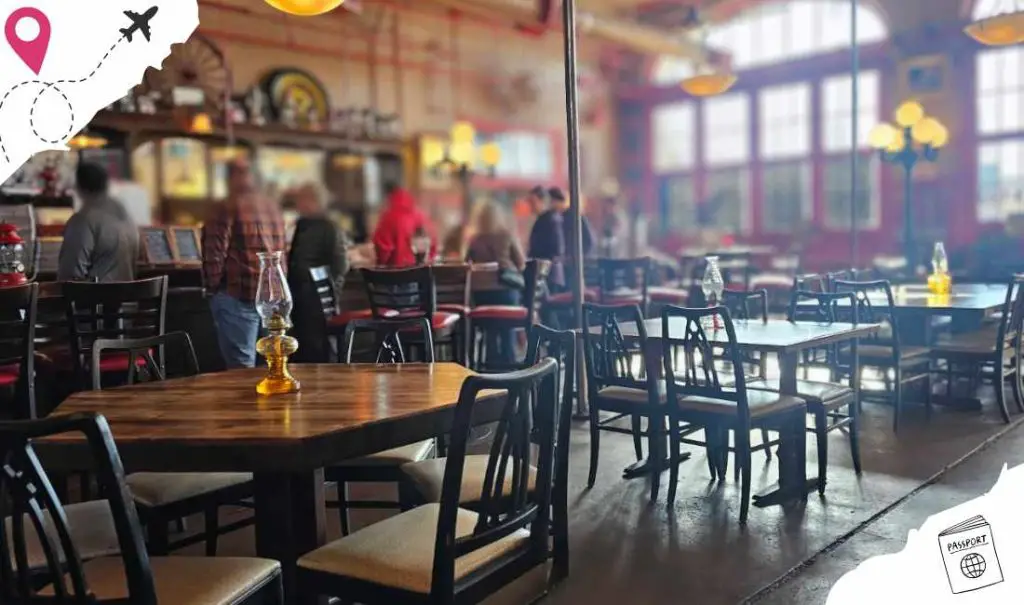A cozy, stylish restaurant interior with wooden tables, black chairs, and large windows letting in natural light, perfect for enjoying flavorful meals and travel-inspired dining experiences.