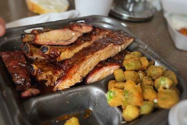 Succulent grilled ribs with crispy fried okra on a metal tray, side dish, delicious barbecue meal at a restaurant, close-up image for food lovers, hearty southern cuisine.