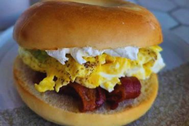 Crispy bacon and fluffy scrambled eggs breakfast sandwich on a toasted bun, perfect for a hearty morning meal. Ideal for breakfast lovers and egg sandwich enthusiasts.