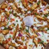 Crispy chicken pizza with vegetables and melted cheese, close-up photo of popular comfort food from American cuisine.