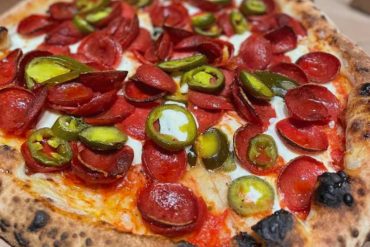 Crispy pepperoni pizza topped with jalapeño slices, fresh mozzarella, and zesty tomato sauce, perfect for pizza lovers seeking authentic flavors and a spicy kick from added peppers.