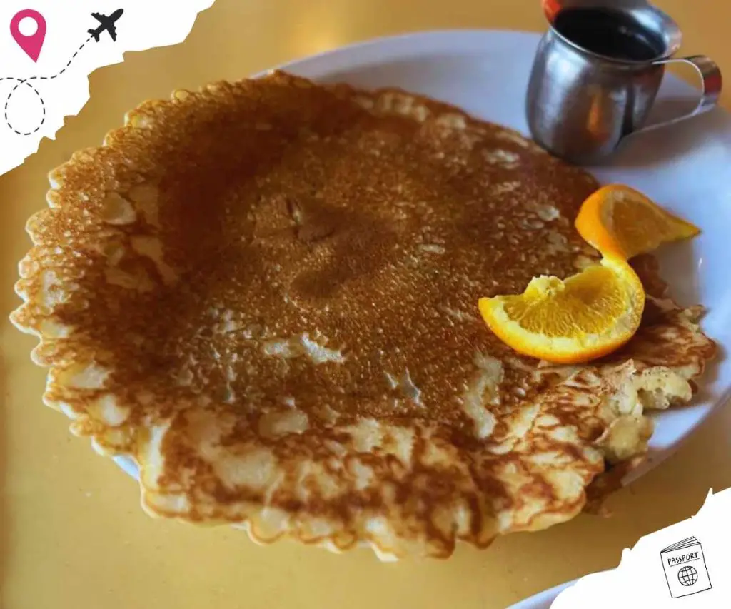 Thin crispy Belgian waffle topped with powdered sugar, served with fresh orange slices, served with a side of syrup. Perfect for breakfast or brunch, popular tourist destination cuisine.