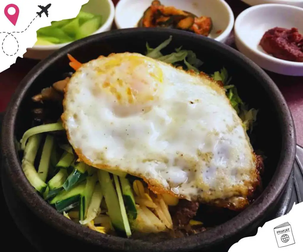 Egg-topped Bibimbap served in a stone bowl with fresh vegetables, capturing authentic Korean cuisine experience.