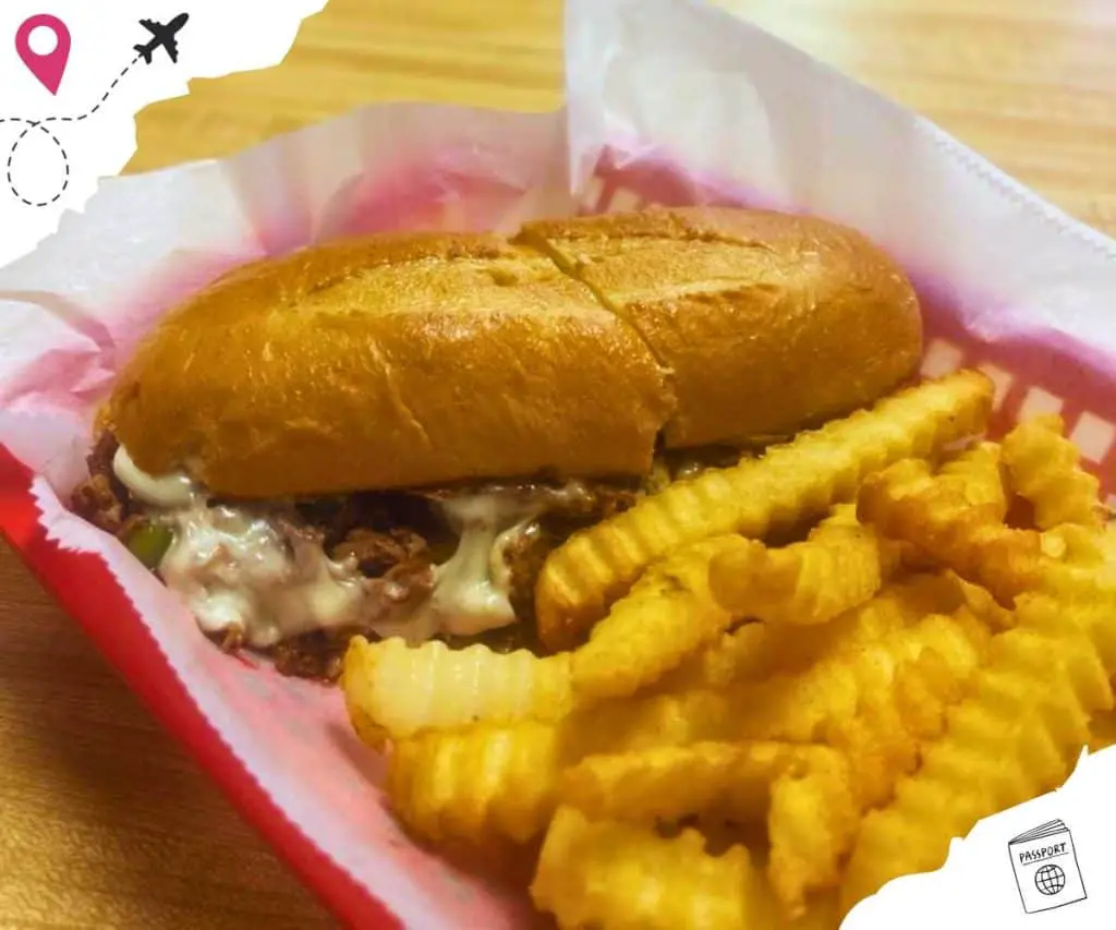Philly cheesesteak sandwich with a side of wavy fries.