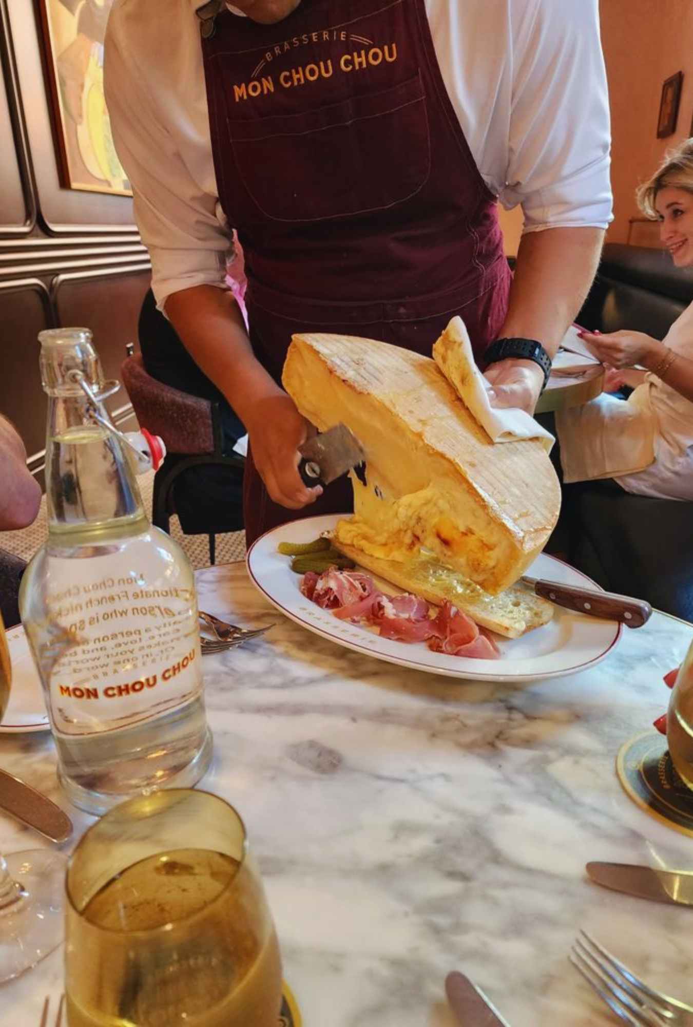 cheese wedge being sliced on a baguette at brasserie Mon chou chou in San Antonio texas