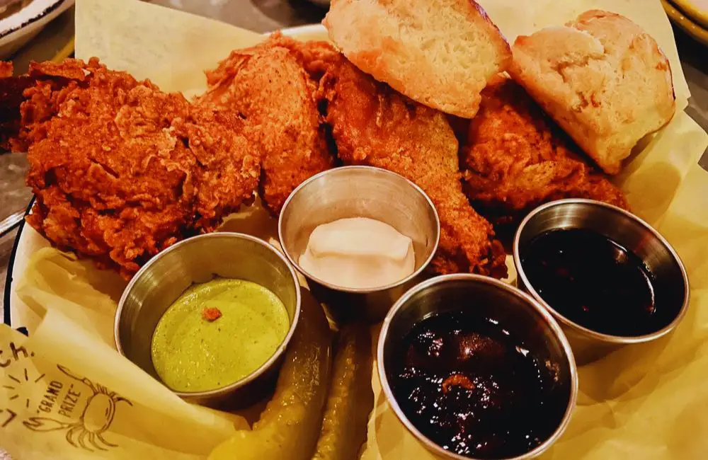Half fried chicken with biscuits, pickles, green harissa, oyster aioli, and jams at la Lucha inHouston, TX