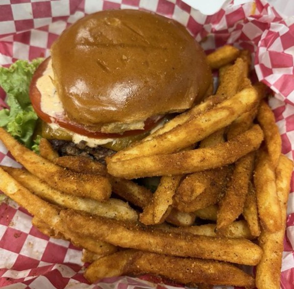 Burger with seasoned fries in Cleave Land Grill located in Strongsville, OH.