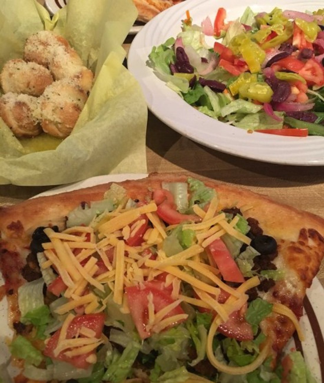 Taco pizza slice, Greek salad and garlic rolls in PizzAmore located in Albany, OR.