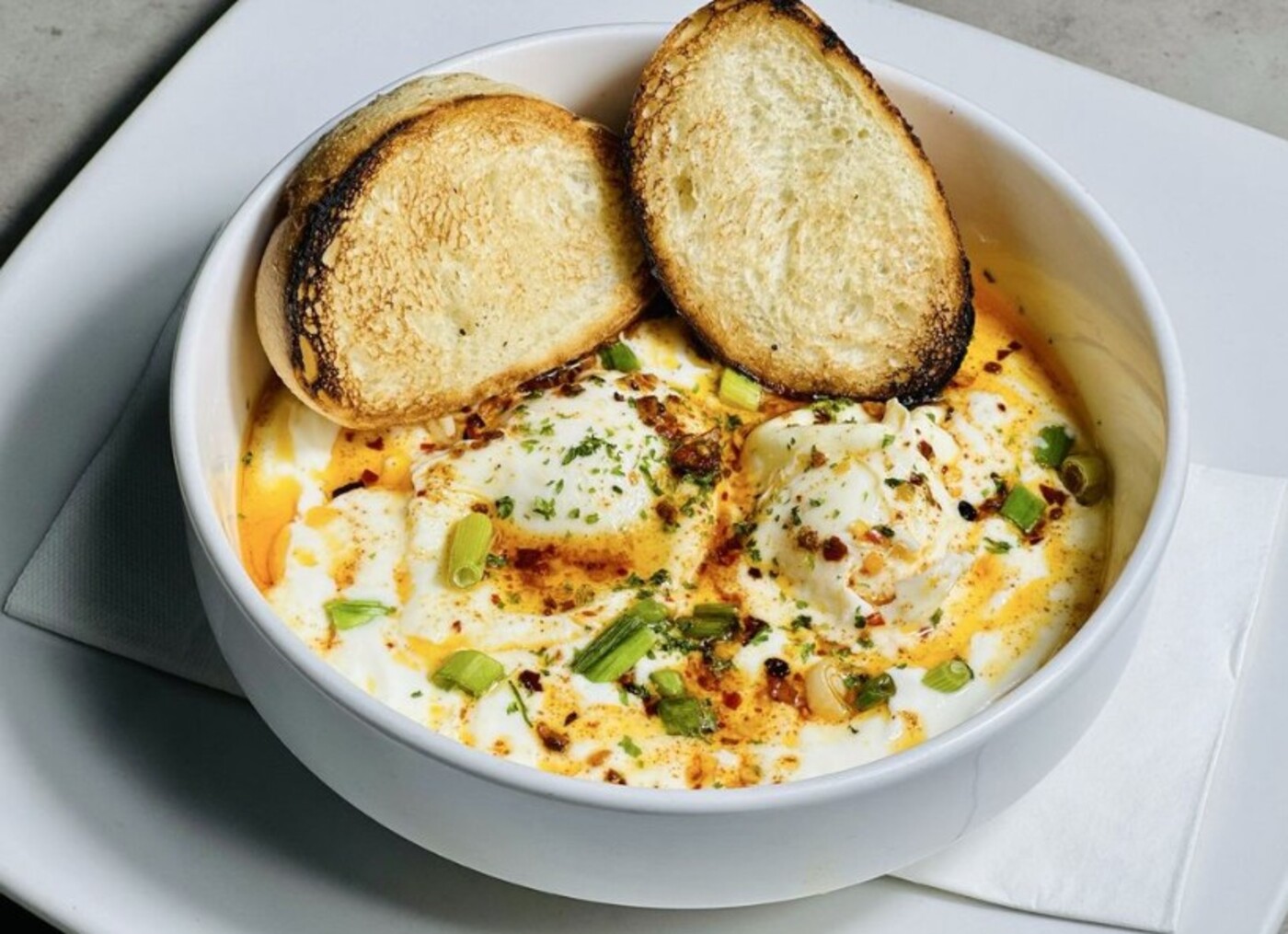 Santorini Silk- 2 poached eggs, savory Yogurt and chili oil drizzle at Mom's Kitchen located in Fort Lauderdale, FL. 