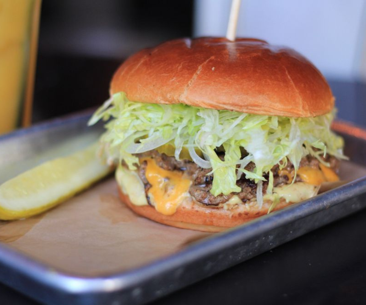 A fully loaded burger serving filled with veggies and meat