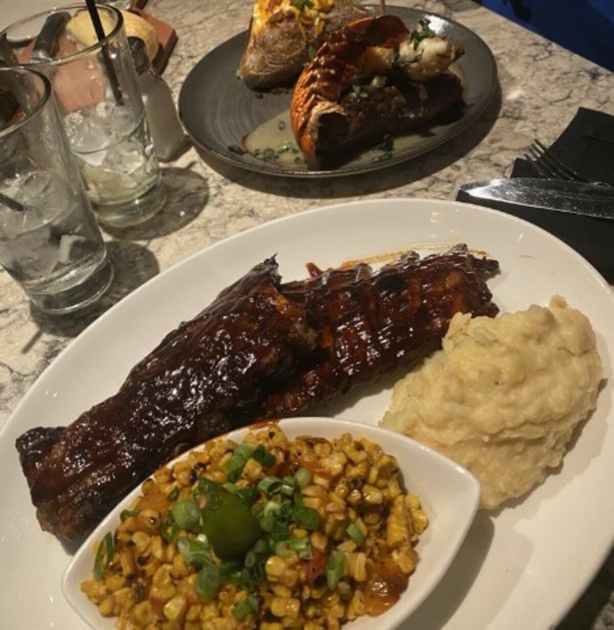 Baby Back Ribs , Grilled Street Corn, Parmesan Mashed Potatoes, Wood Grilled NY Strip at Firebirds Wood Fired Grill located in Murfreesboro, TN. 
