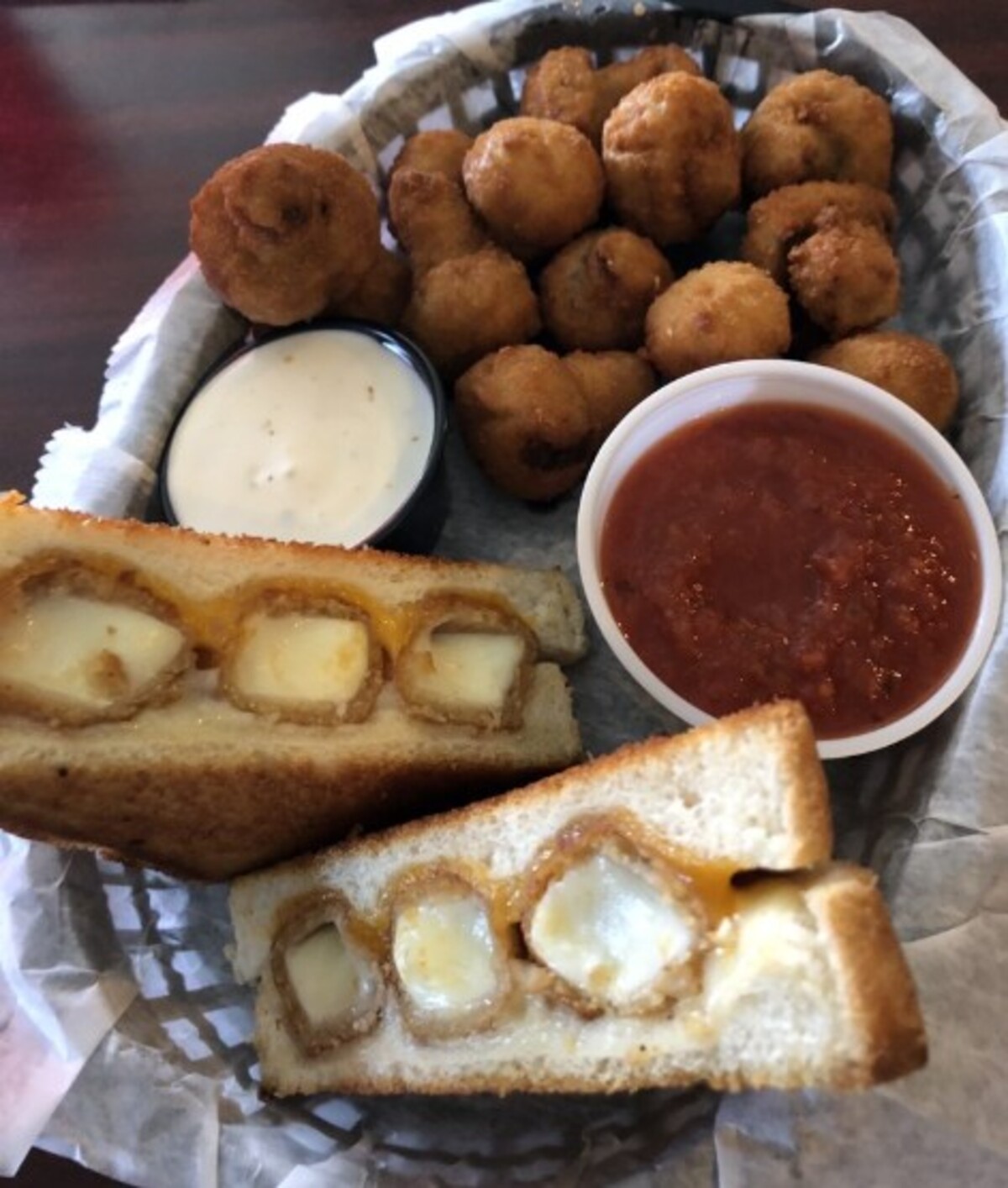Grilled cheese sandwich made with mozzarella sticks and served with marinara sauce. Fried mushrooms on the side at Savage's Ale House located in Muncie, IN.