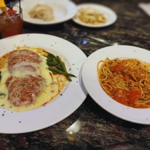Veal Parm topped with provolone on the left and linguine with red clam sauce on the right